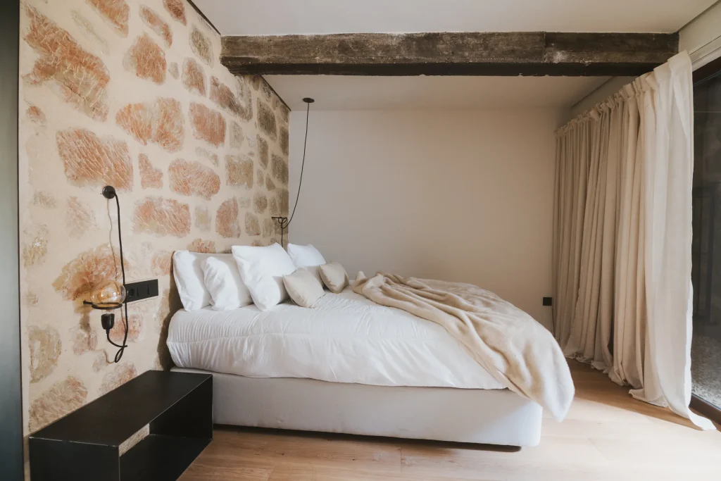 Cama de matrimonio del apartamento 5 bajo una estructura de madera y piedra vista.