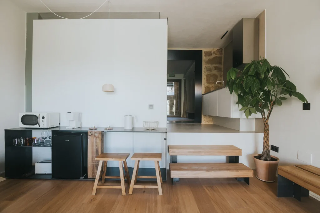 Cocina abierta del apartamento 5 con armarios blancos y encimera de madera.