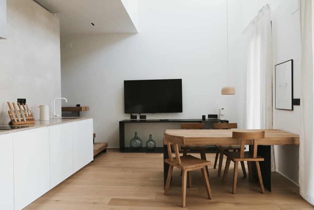 Zona de estar y cocina abierta del apartamento 4, con televisor y ventanales.