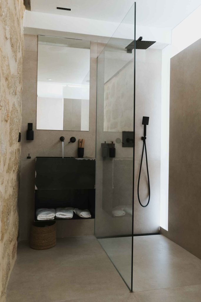 Ducha del apartamento 2 con mampara de cristal y grifería negra.