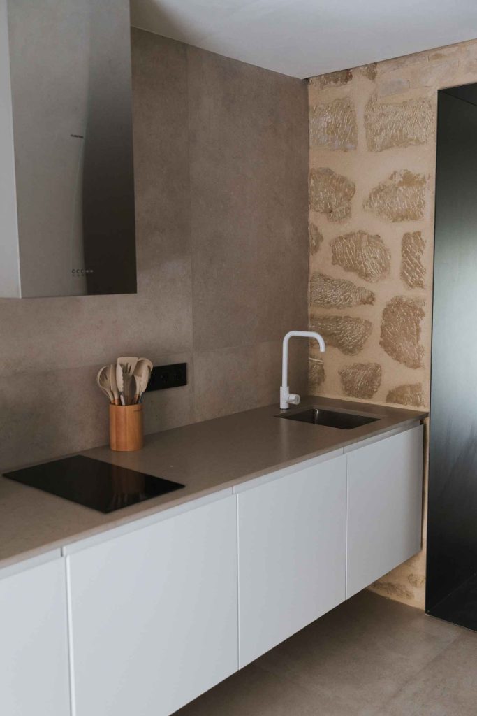 Fregadero de la cocina del apartamento 2 ante un muro de piedra vista.