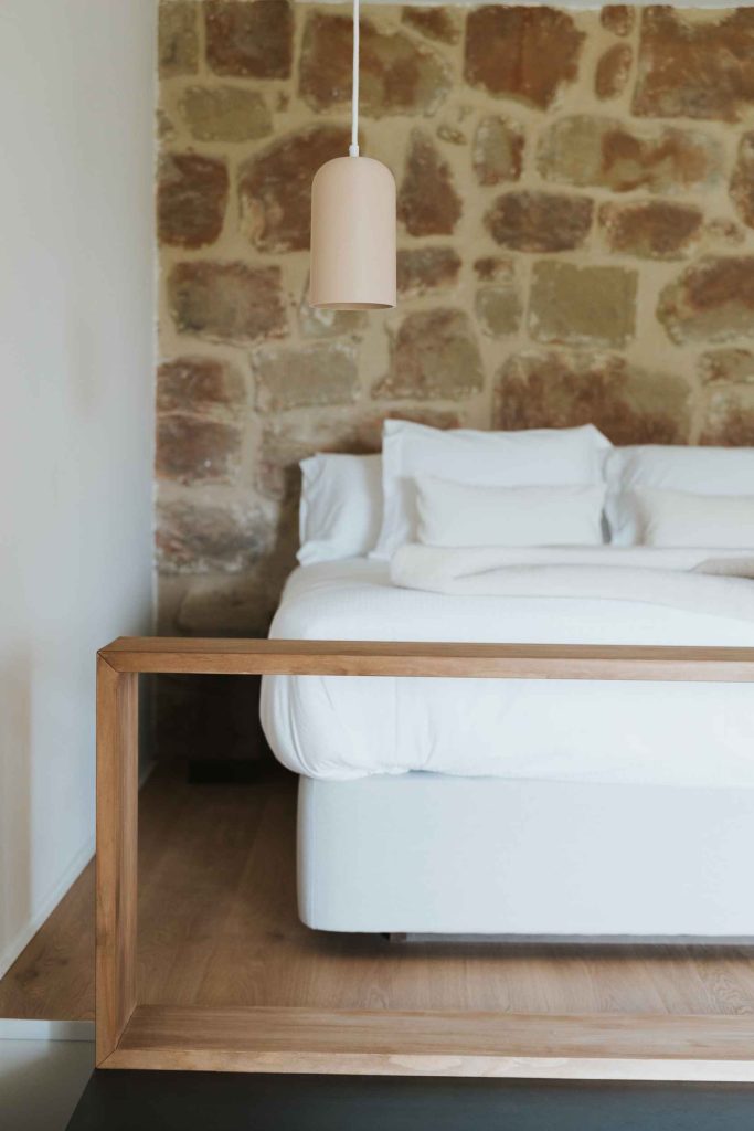 Cama de matrimonio del apartamento 2 junto a un muro de piedra original.