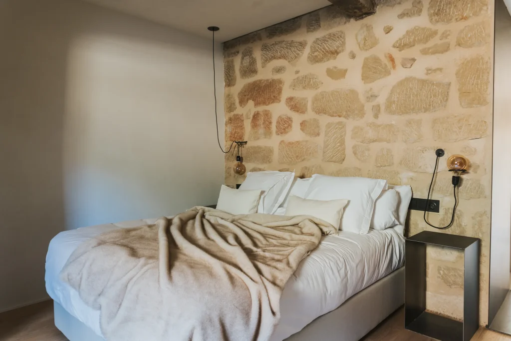 Dormitorio del apartamento 6 con cama de matrimonio y pared de piedra vista.