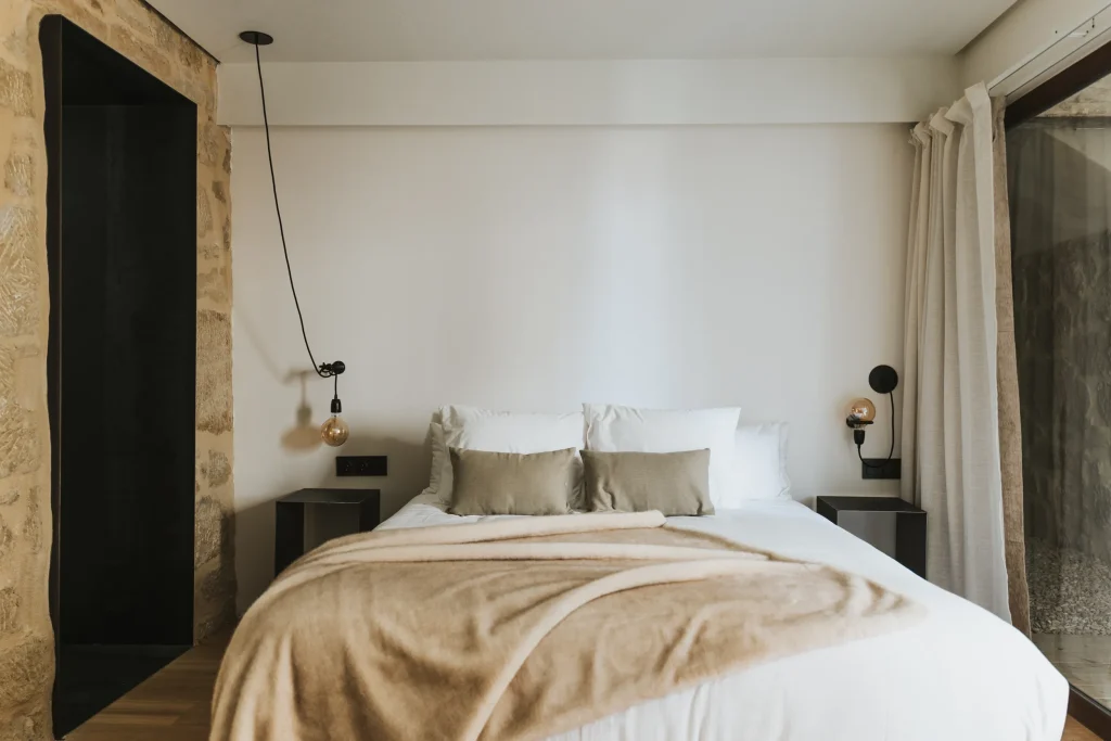 Cama del apartamento 3 con ropa blanca y pared de tonos claros.