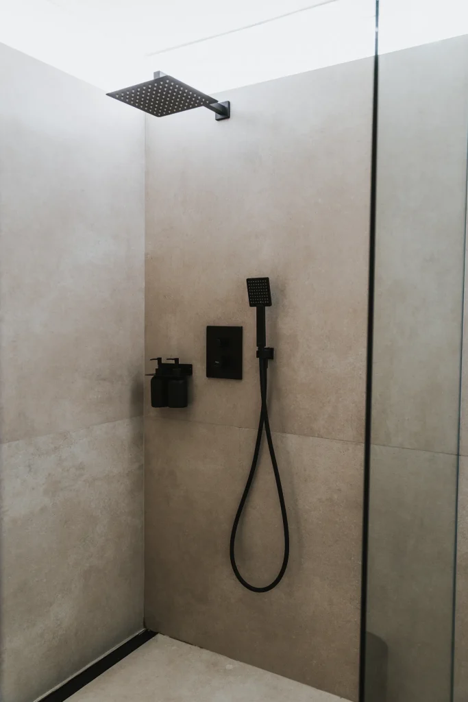 Ducha del apartamento 3 con mampara de cristal y grifería negra.