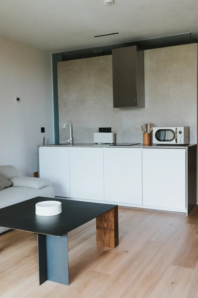 Frente de cocina del apartamento 3 con microondas y armarios blancos.