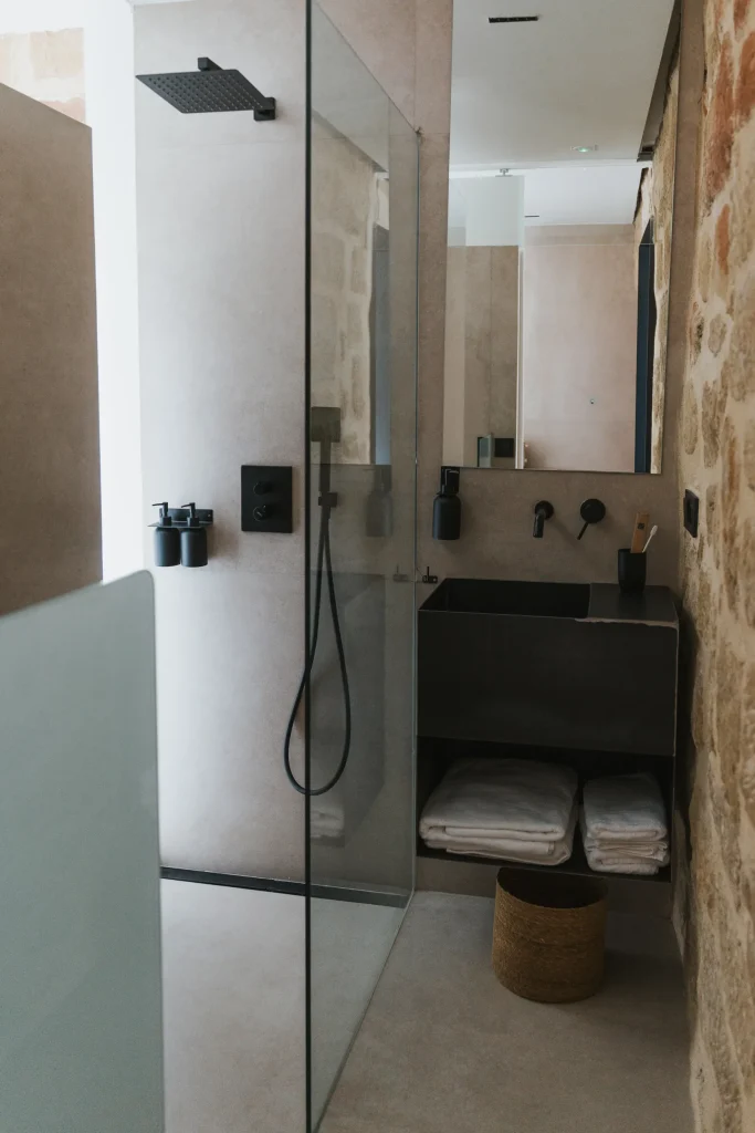 Baño del apartamento 1 con lavabo, espejo y ducha en tonos claros.