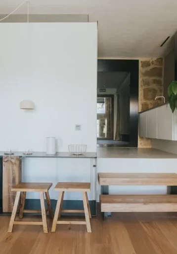 Cocina abierta del apartamento 5 con armarios blancos y encimera de madera.
