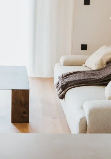 Cama de matrimonio del apartamento 6 junto a un muro de piedra original y lámparas colgantes.
